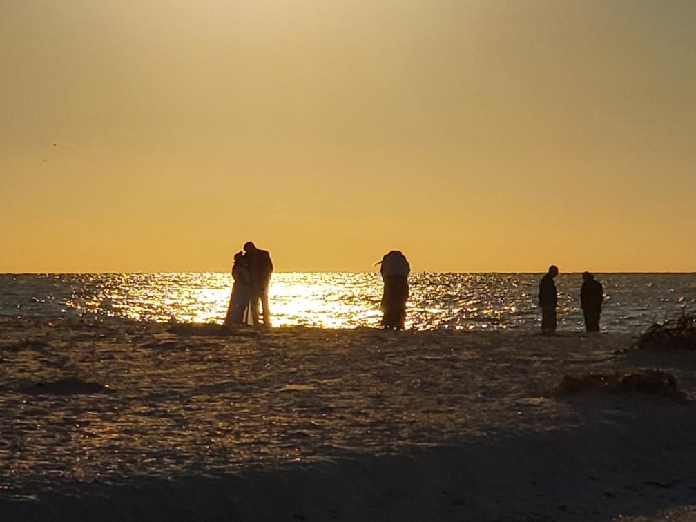 a group of people standing on top of a sandy beach